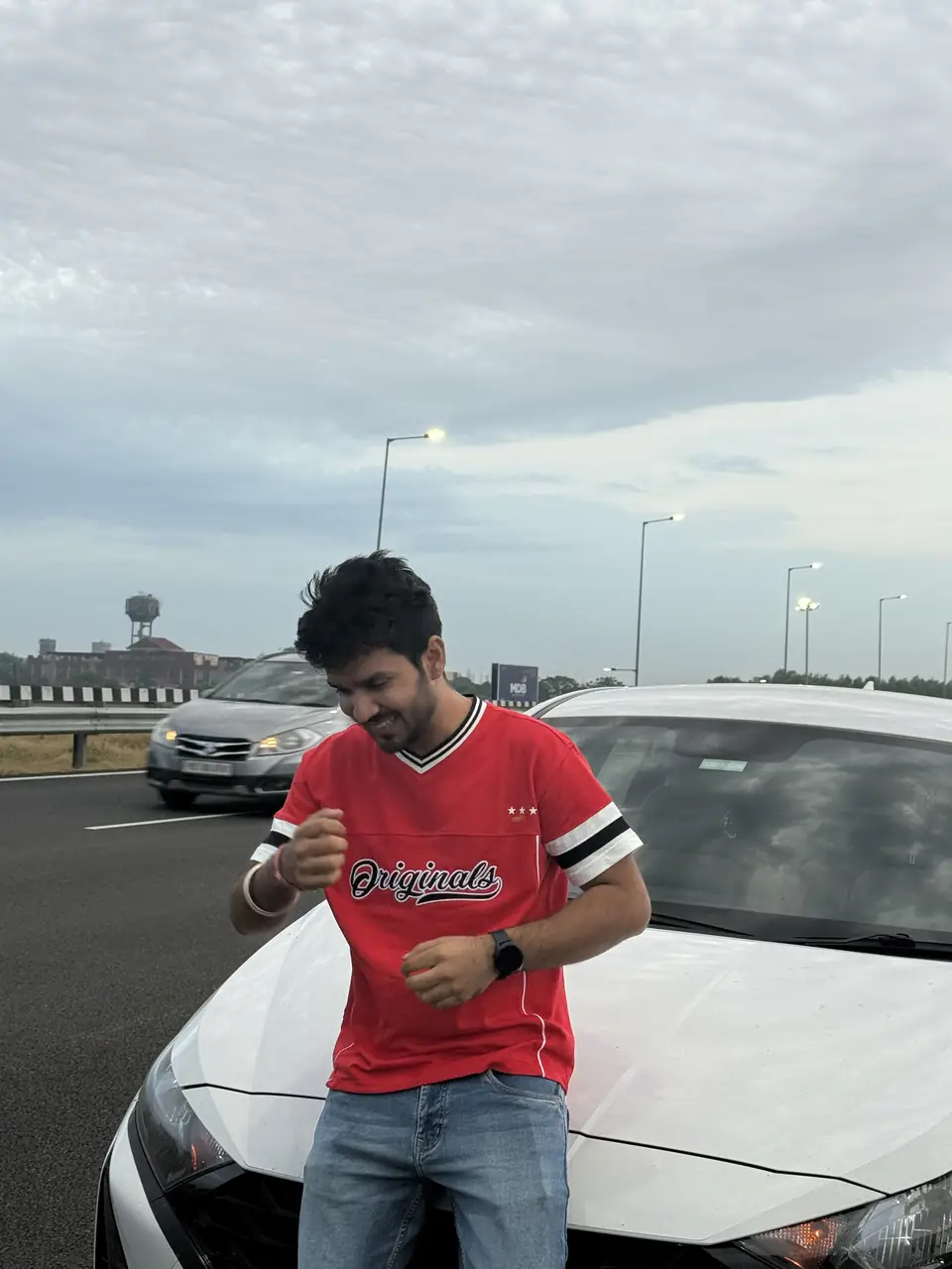 Pritish Bhatti in a red t-shirt looking down and smiling