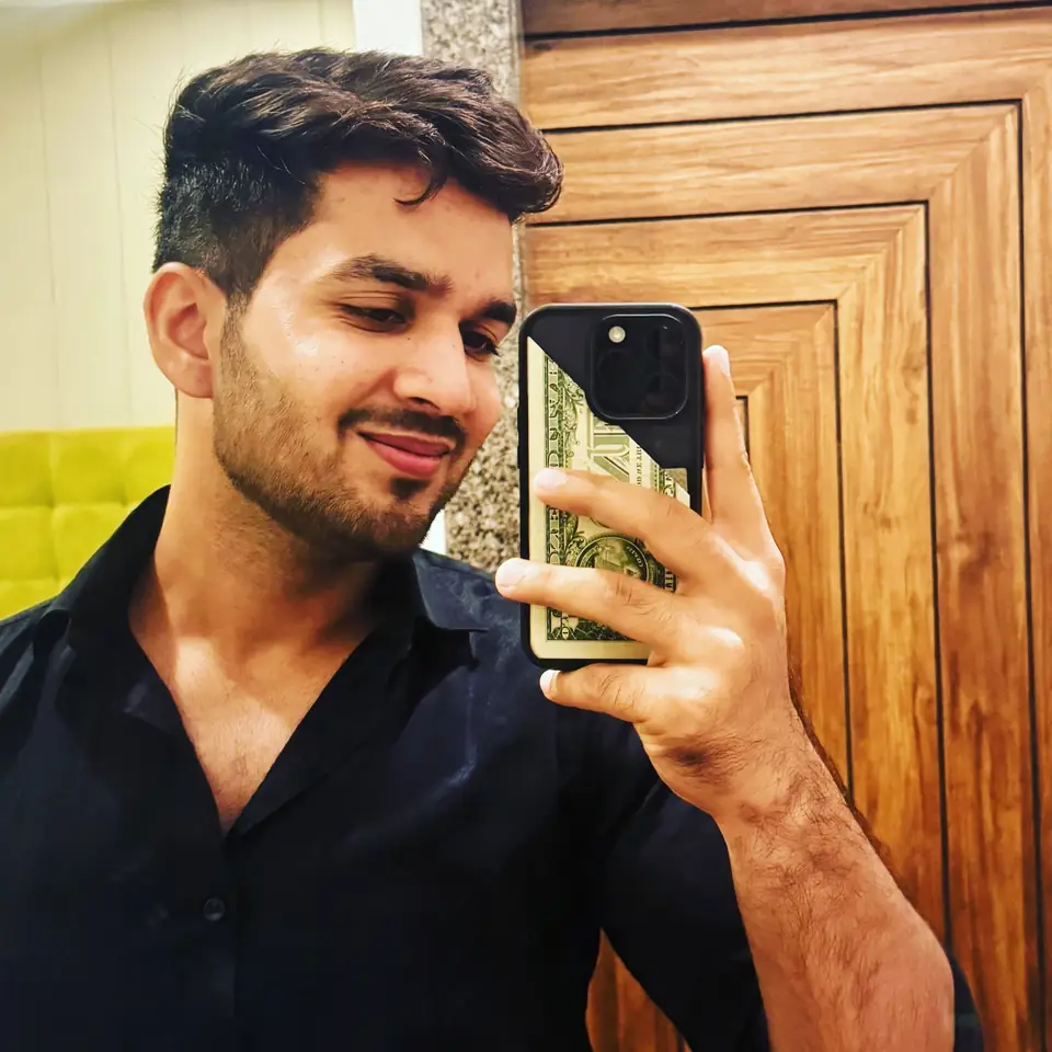 Pritish Bhatti moody mirror portrait in a black shirt against wood panelling